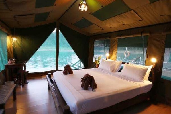 The inside of a safari tent with a lake visible through its large plastic windows