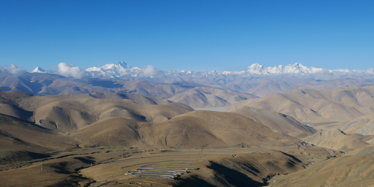 Brown foothills stretching to the horizon, where there is a line of jagged snowy peaks