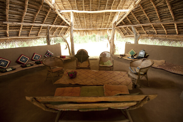A grass-thatched hut at dusk, lit by solar torches