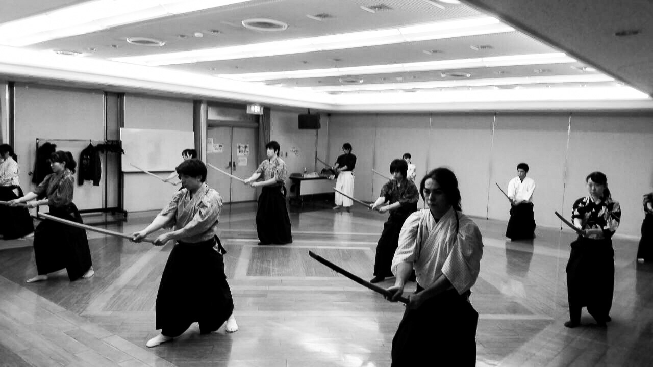 People in traditional Japanese clothes, holding katana swords